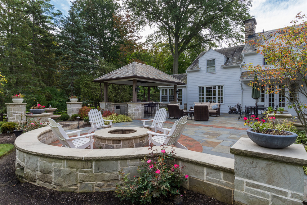 Aménagement d'une terrasse arrière classique de taille moyenne avec une cuisine d'été, des pavés en pierre naturelle et un gazebo ou pavillon.