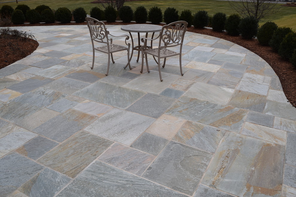 Inspiration for a large back patio in New York with a fire feature, natural stone paving and no cover.