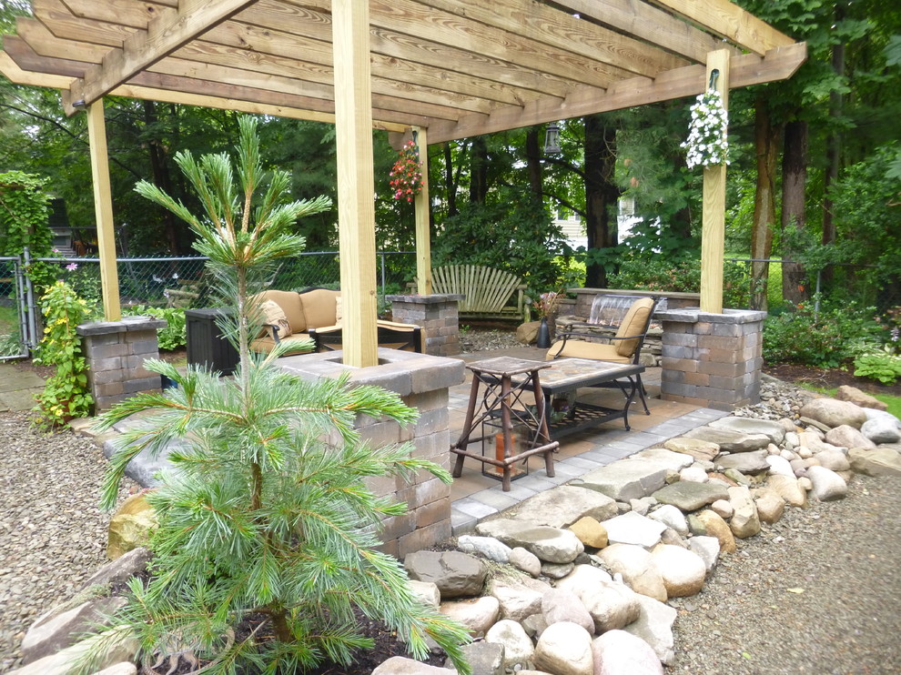 Example of a mid-sized classic backyard stone patio fountain design in New York with a pergola
