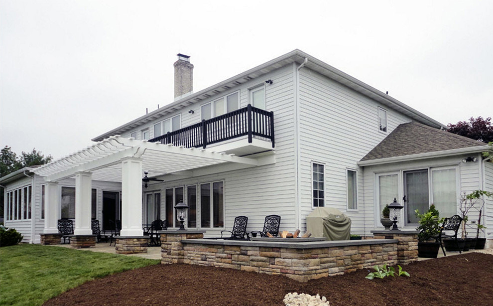 Foto di un grande patio o portico design dietro casa con un focolare, pavimentazioni in pietra naturale e una pergola
