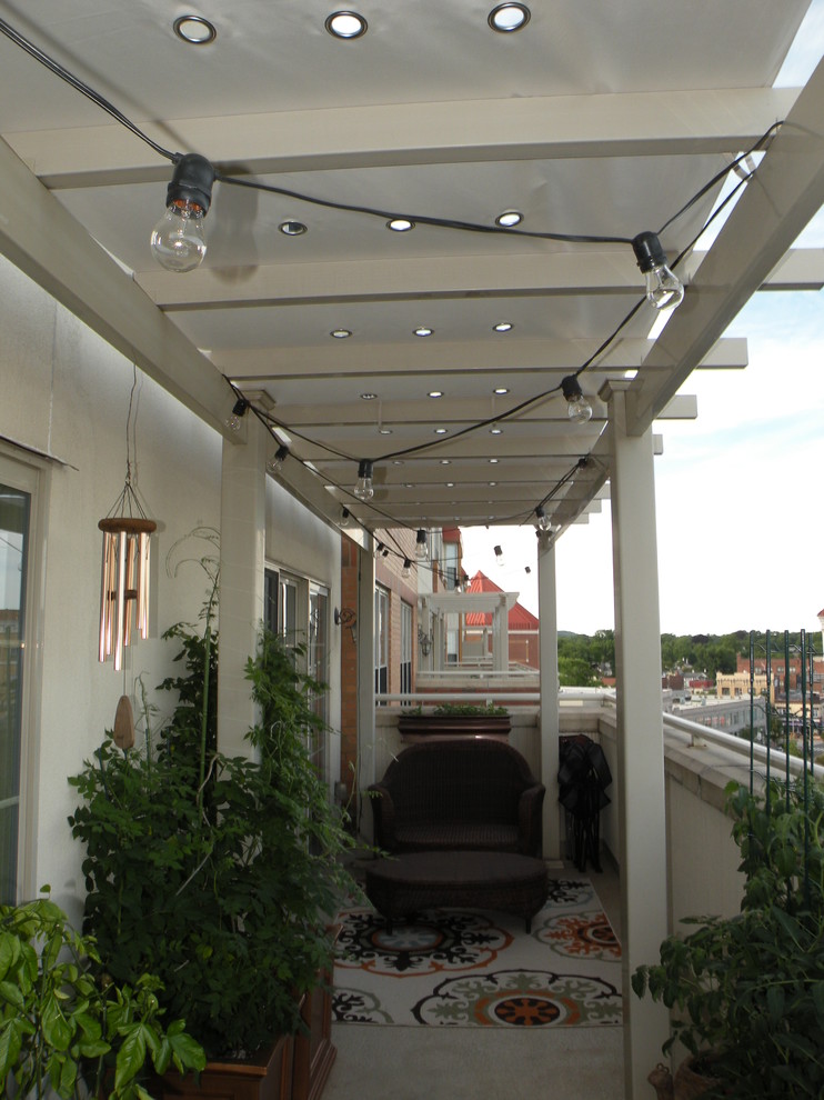 Immagine di un piccolo patio o portico stile marinaro dietro casa con lastre di cemento e un parasole