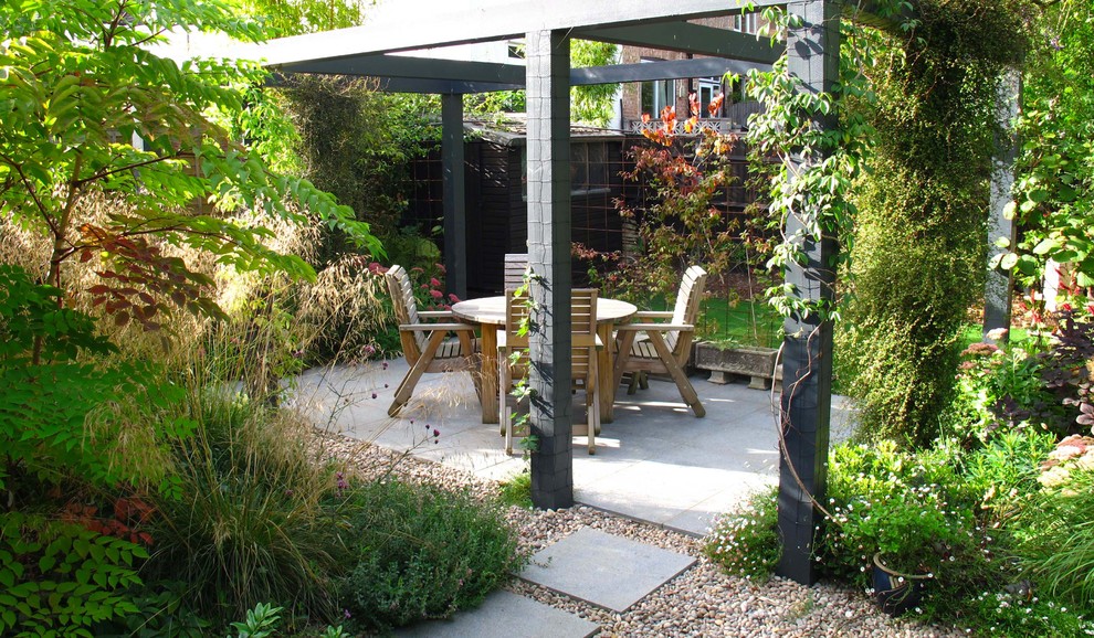 Imagen de patio contemporáneo de tamaño medio en patio trasero con adoquines de piedra natural