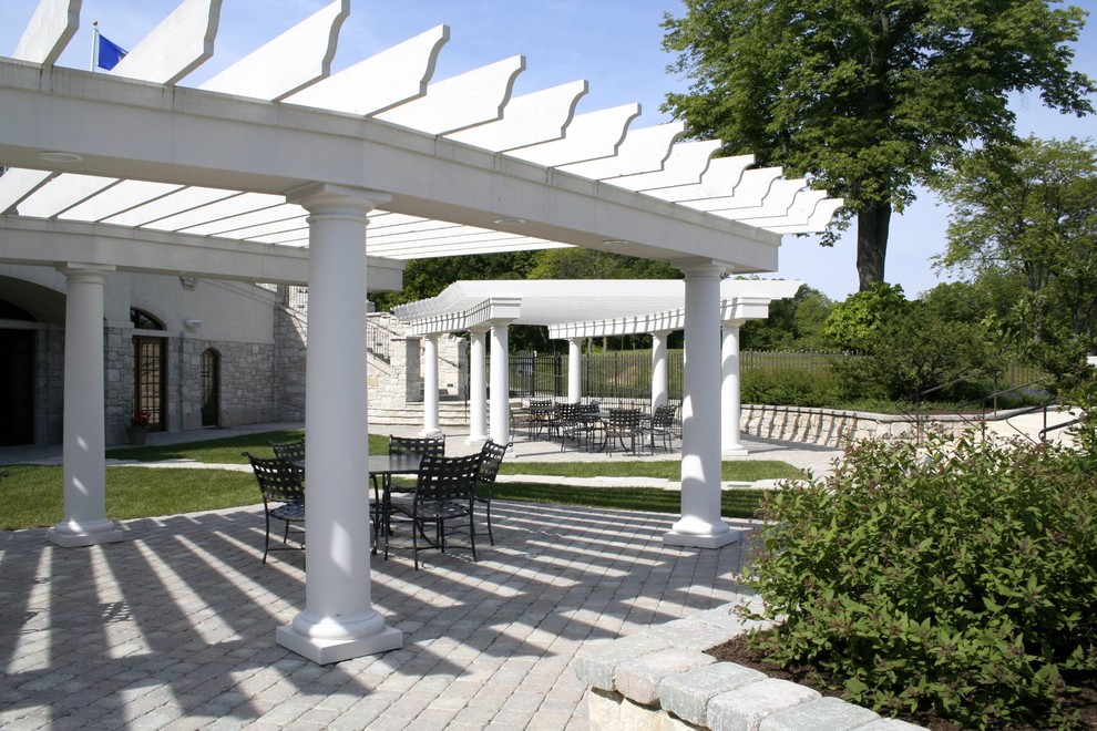 Immagine di un grande patio o portico classico dietro casa con pavimentazioni in mattoni e una pergola
