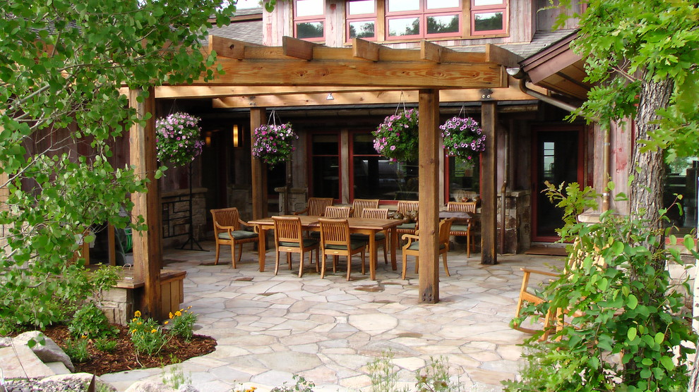 Idee per un grande patio o portico stile rurale dietro casa con pavimentazioni in pietra naturale e una pergola