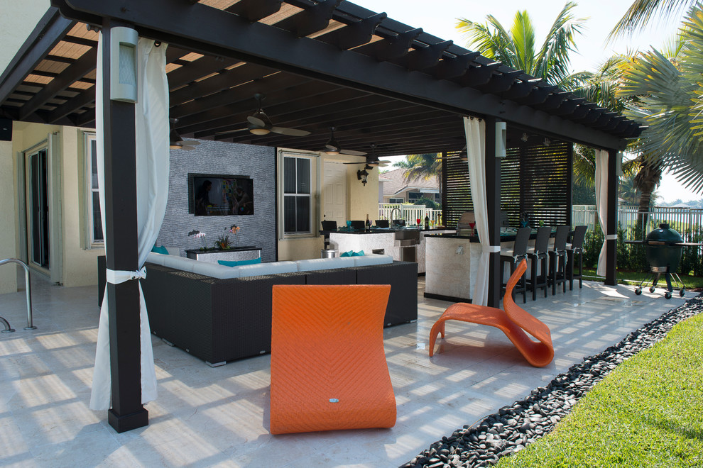 Huge trendy backyard stone patio kitchen photo in Miami with a pergola