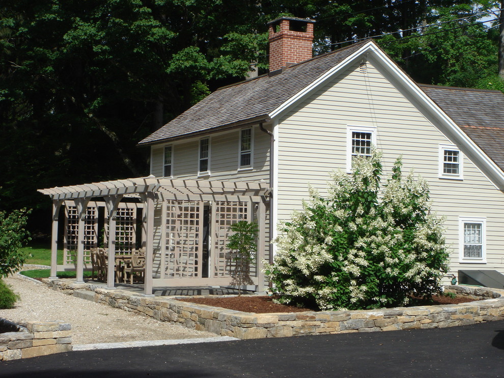 Esempio di un patio o portico country di medie dimensioni e davanti casa con pavimentazioni in pietra naturale e una pergola