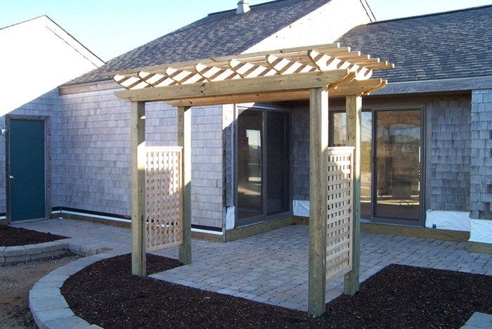 Ejemplo de patio de estilo americano en patio lateral con adoquines de hormigón y pérgola