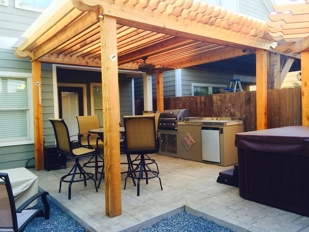 Modelo de patio clásico de tamaño medio en patio trasero con cocina exterior, suelo de hormigón estampado y pérgola
