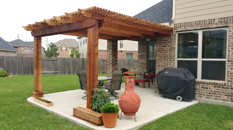 Immagine di un piccolo patio o portico american style dietro casa con lastre di cemento e una pergola