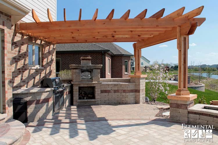 Cette photo montre une terrasse arrière chic de taille moyenne avec une cuisine d'été, des pavés en béton et une pergola.