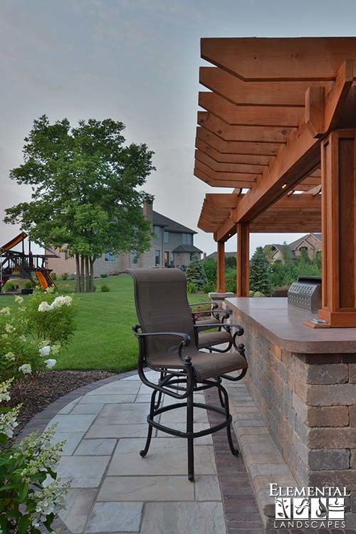 Imagen de patio clásico de tamaño medio en patio trasero con cocina exterior, adoquines de hormigón y pérgola