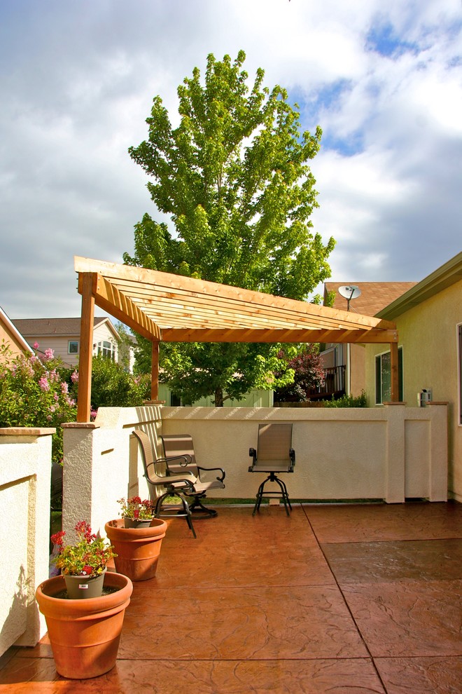Idee per un patio o portico classico di medie dimensioni e dietro casa con cemento stampato e una pergola