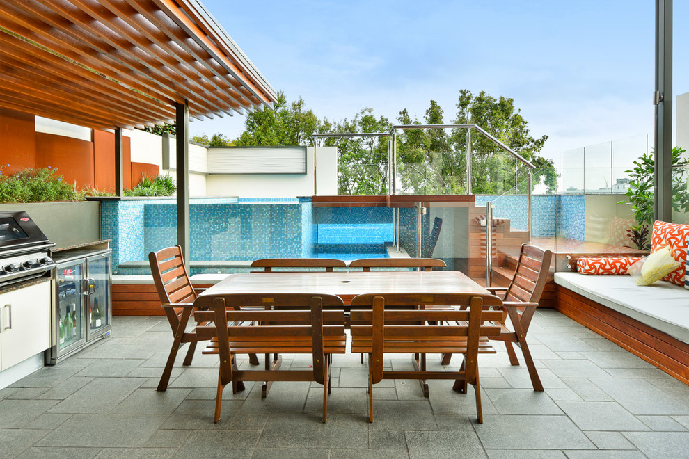 Inspiration pour une terrasse design de taille moyenne avec une cuisine d'été, des pavés en pierre naturelle et une pergola.