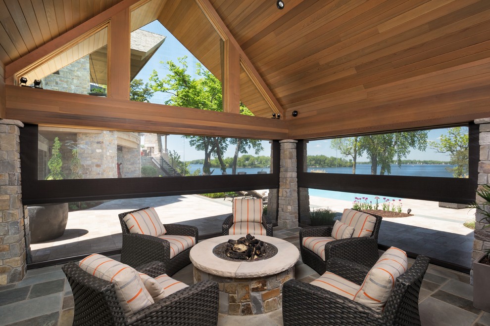 Réalisation d'une grande terrasse arrière tradition avec un foyer extérieur, des pavés en pierre naturelle et un gazebo ou pavillon.