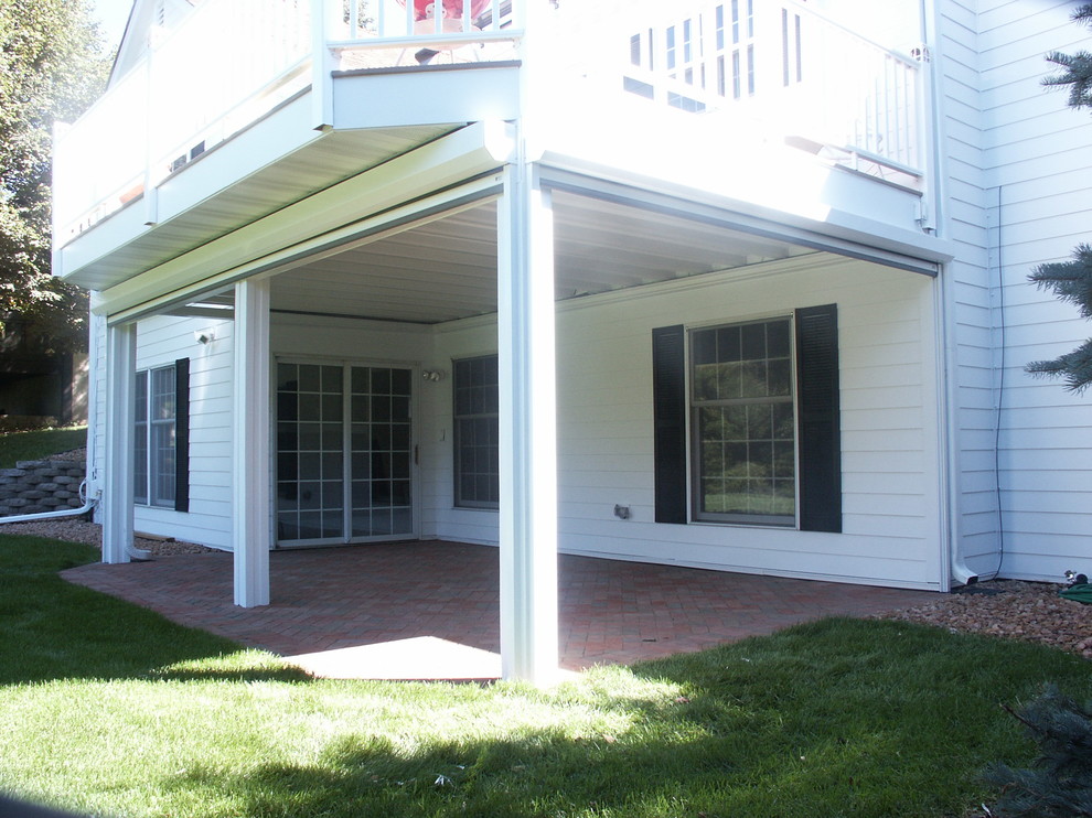Exempel på en liten klassisk uteplats på baksidan av huset, med marksten i tegel och takförlängning