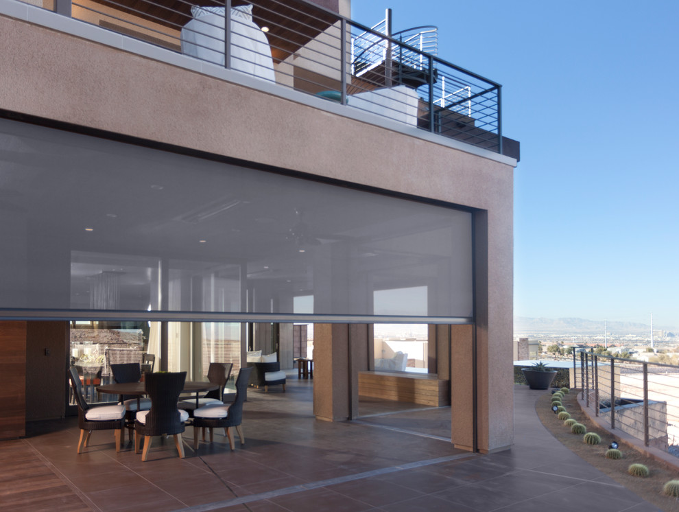Cette image montre une grande terrasse arrière minimaliste avec une cuisine d'été, du carrelage et une extension de toiture.