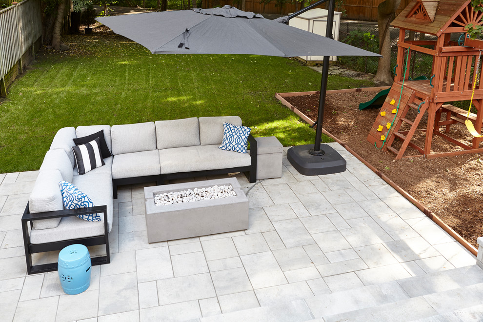 Large minimalist backyard concrete paver patio photo in Toronto with a fire pit and an awning