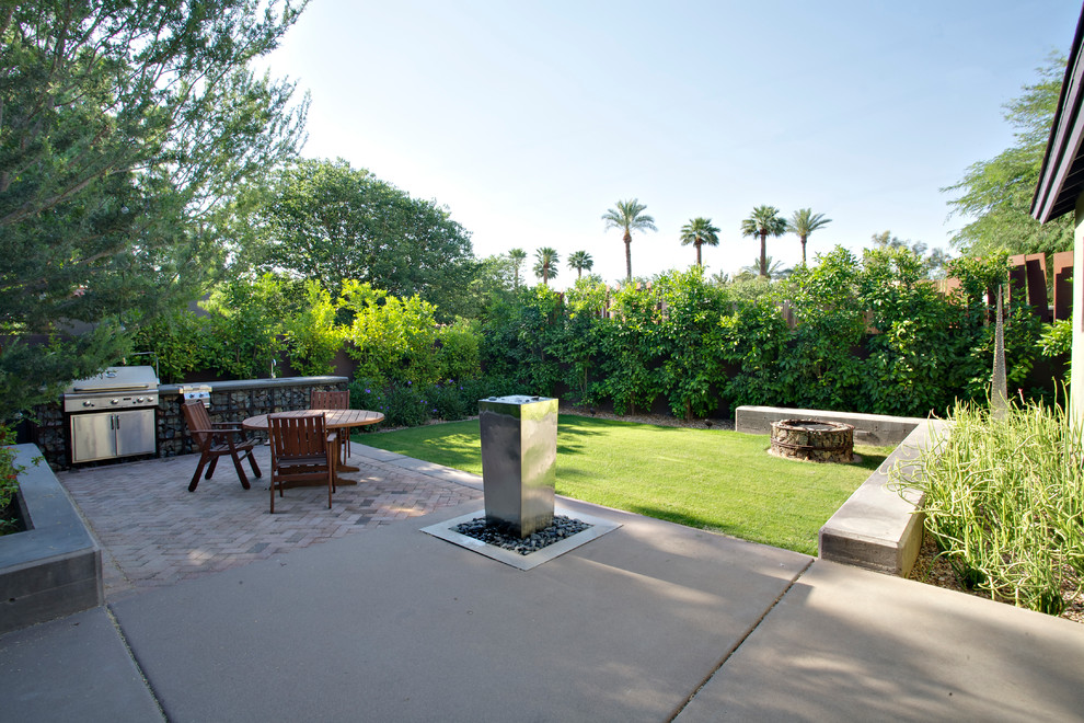 Photo of a medium sized urban back patio in Phoenix with a water feature, concrete slabs and no cover.
