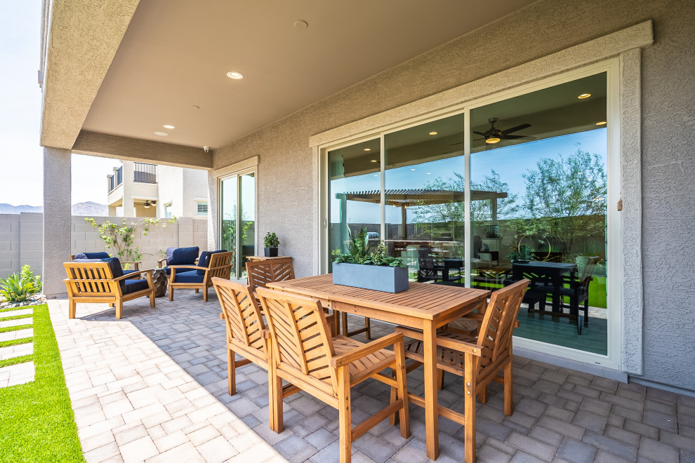 This is an example of a medium sized contemporary back patio in Phoenix with brick paving and a roof extension.