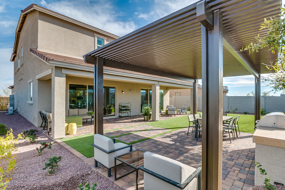 Geräumiger, Überdachter Moderner Patio hinter dem Haus mit Outdoor-Küche und Pflastersteinen in Phoenix
