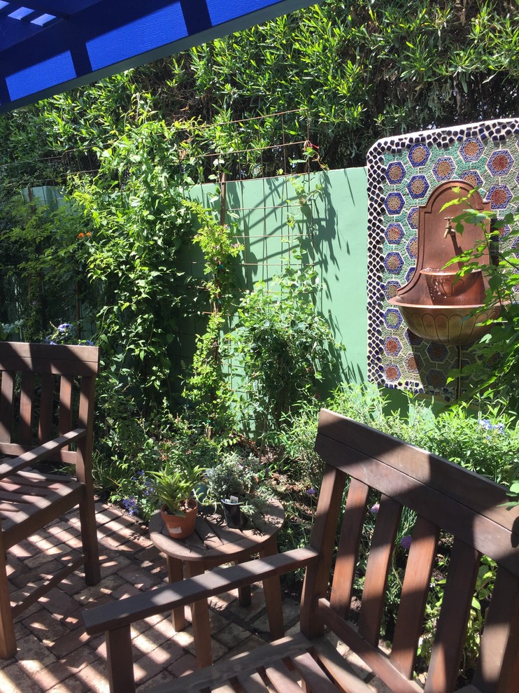 Foto de patio bohemio pequeño en patio trasero con fuente, adoquines de ladrillo y pérgola