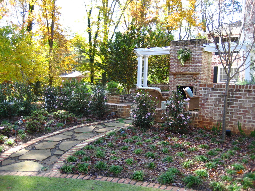Diseño de patio clásico en patio trasero con adoquines de piedra natural y pérgola