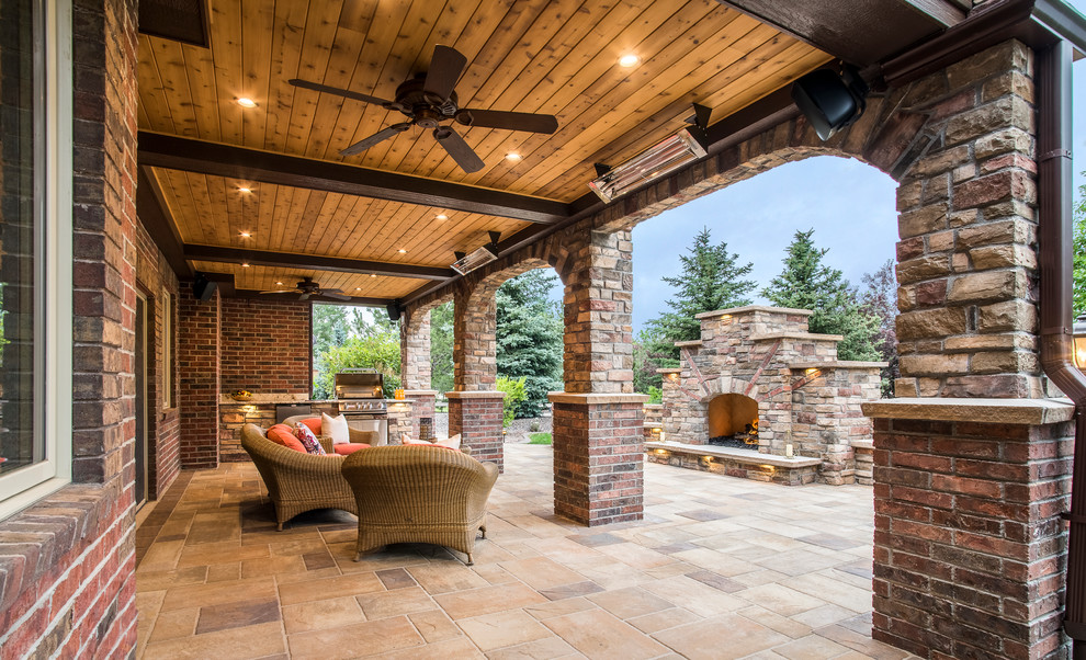 Example of a mountain style backyard stone patio design in Denver with a roof extension
