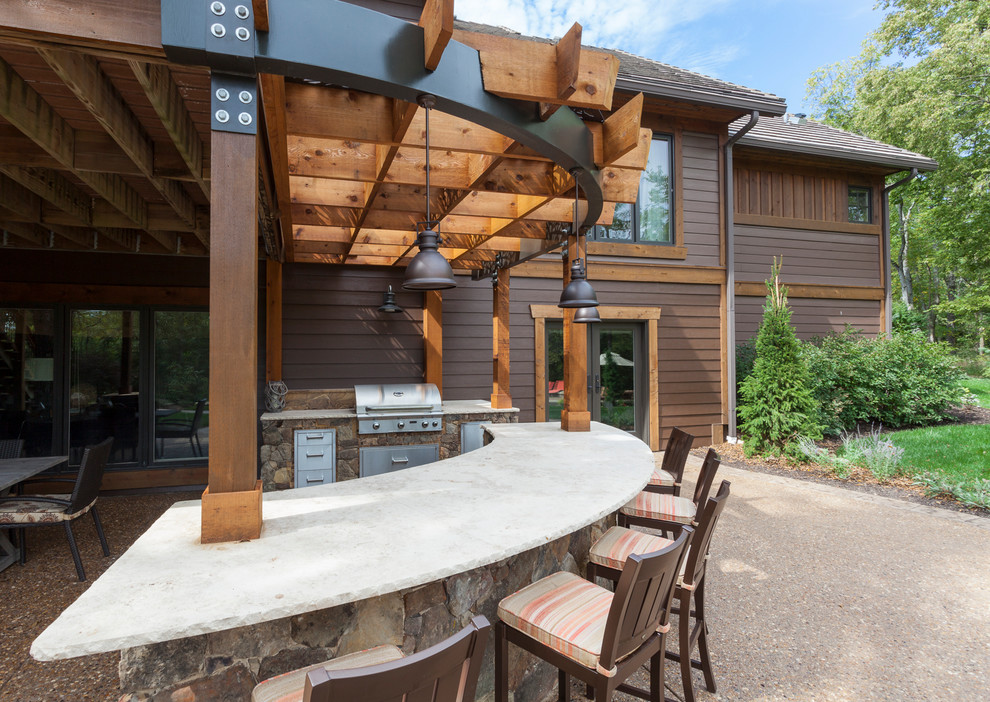 Modelo de patio de estilo americano grande en patio trasero con cocina exterior, losas de hormigón y pérgola