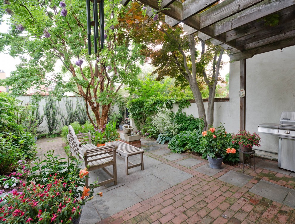 Ejemplo de patio tradicional renovado de tamaño medio sin cubierta en patio trasero con fuente y adoquines de ladrillo