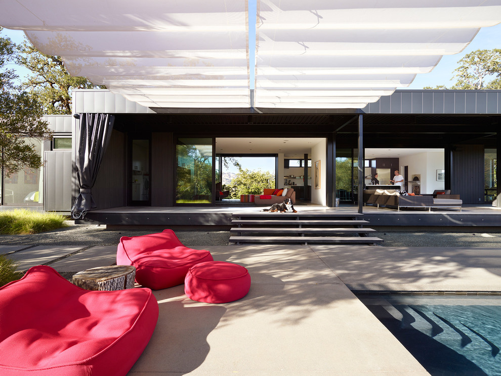 Foto di un patio o portico minimalista dietro casa con lastre di cemento e un parasole