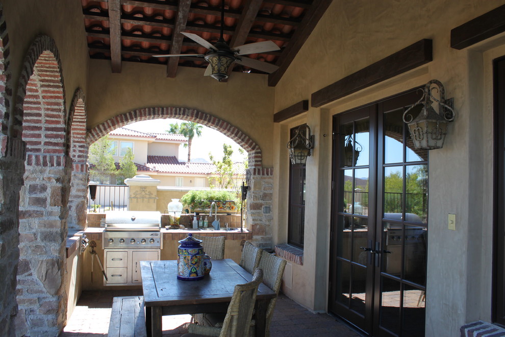 Mid-sized tuscan backyard patio kitchen photo in Las Vegas with a roof extension