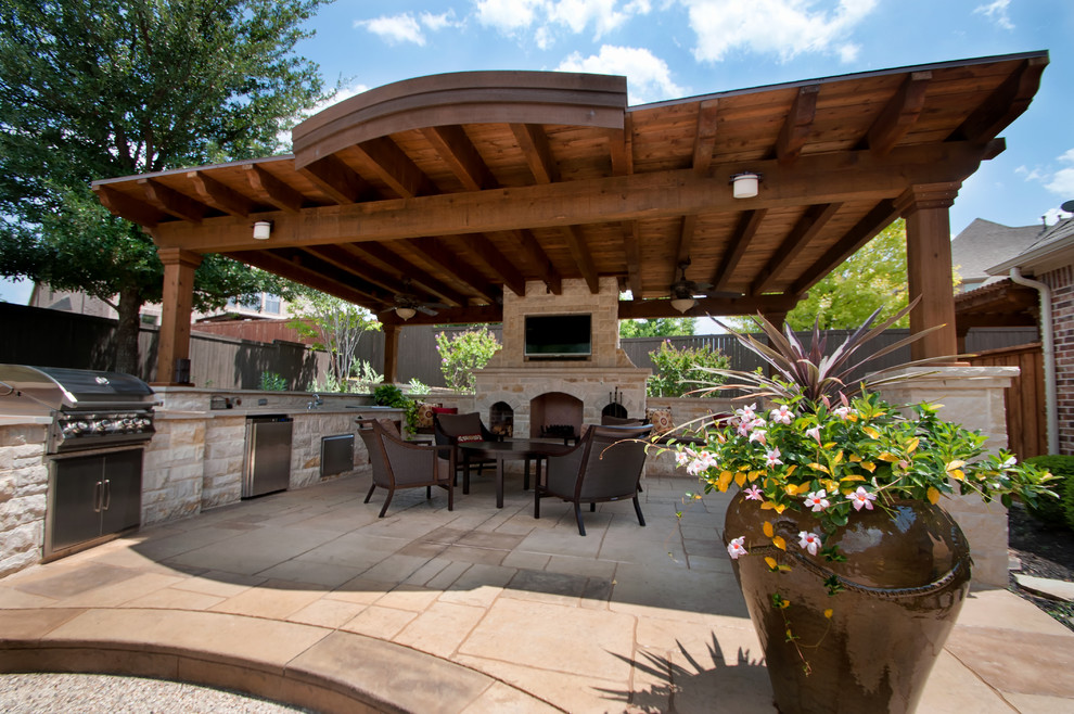 Modelo de patio tradicional grande en patio trasero con cocina exterior, adoquines de hormigón y cenador