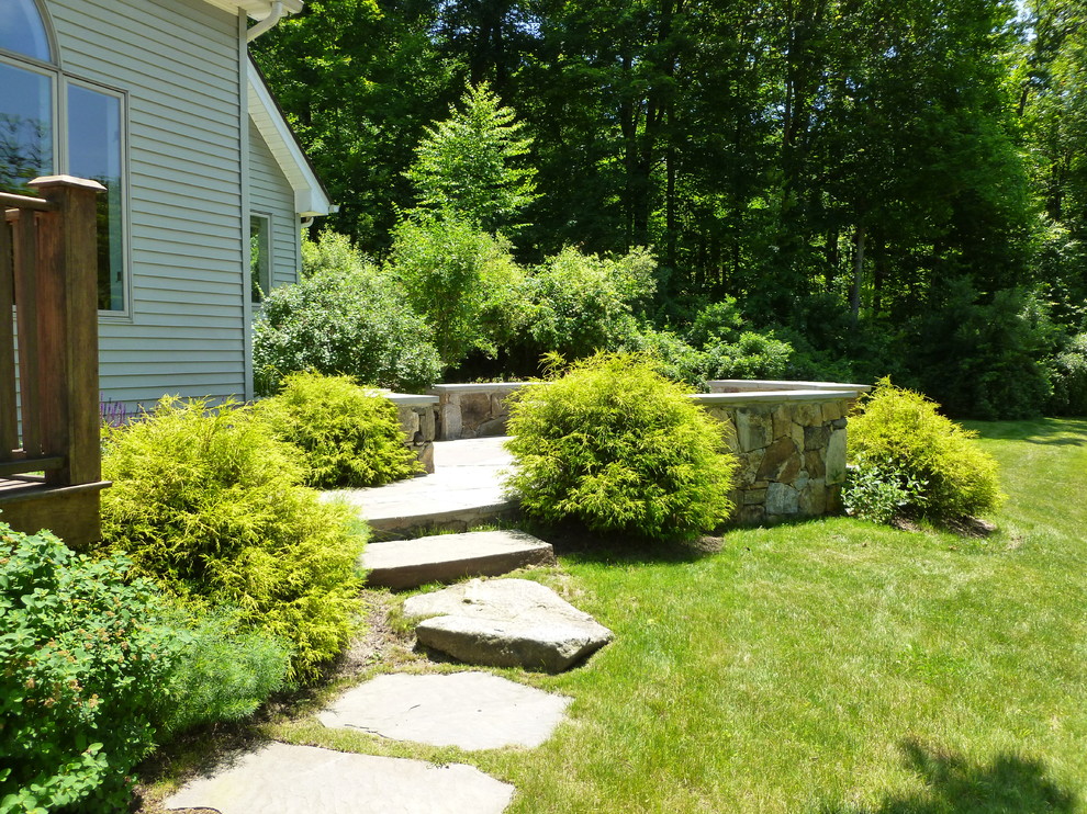 This is an example of a mid-sized traditional backyard stone landscaping in New York.