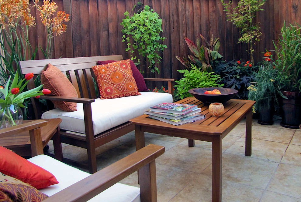 Idee per un piccolo patio o portico tropicale in cortile con un giardino in vaso e piastrelle
