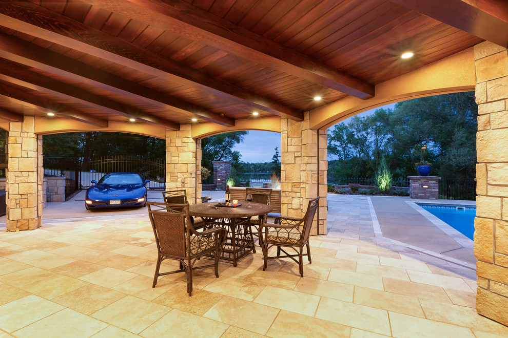 Immagine di un patio o portico tradizionale di medie dimensioni e dietro casa con pavimentazioni in pietra naturale e un tetto a sbalzo