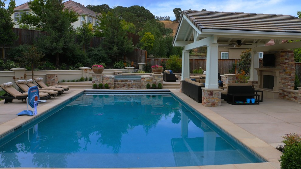 Exempel på en stor klassisk pool på baksidan av huset, med marksten i betong