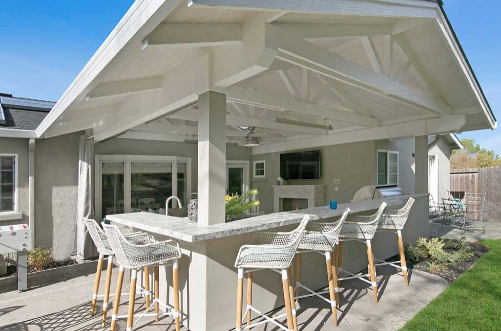 На фото: двор среднего размера на заднем дворе в стиле неоклассика (современная классика) с летней кухней, покрытием из декоративного бетона и навесом