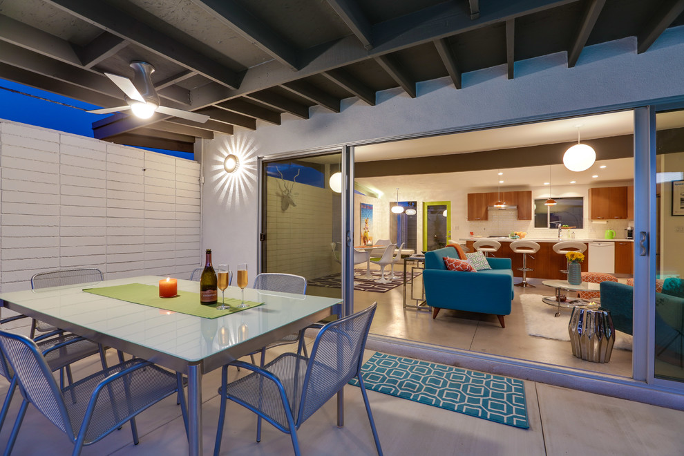 Idee per un patio o portico minimalista di medie dimensioni e dietro casa con pavimentazioni in cemento e un tetto a sbalzo