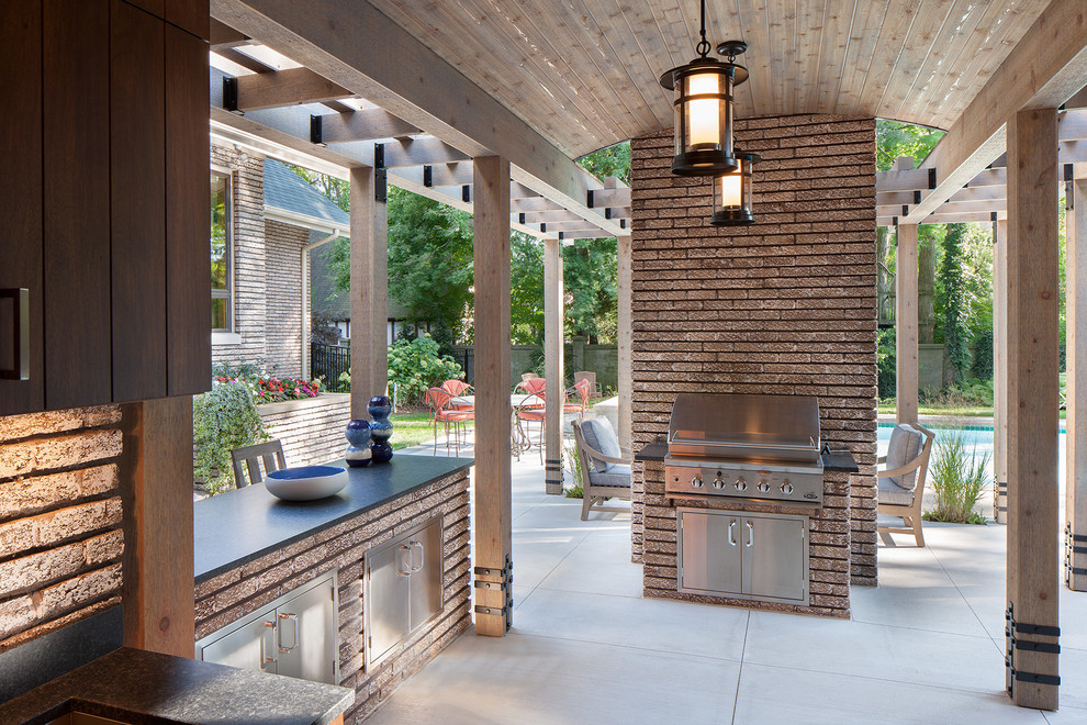Réalisation d'une terrasse arrière design avec une cuisine d'été et des pavés en béton.