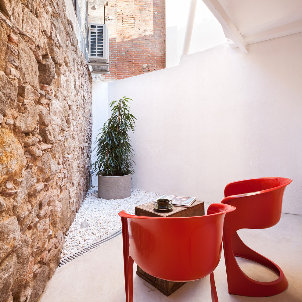 This is an example of a contemporary patio in Barcelona with concrete slabs and a roof extension.