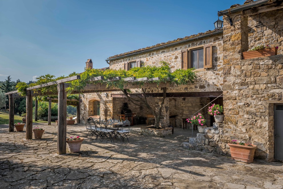 This is an example of a large farmhouse side patio in Florence with natural stone paving and a pergola.
