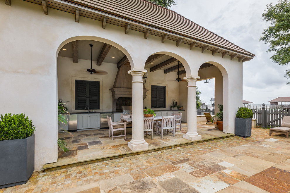Inspiration for an expansive traditional back patio in Miami with an outdoor kitchen, natural stone paving and a roof extension.