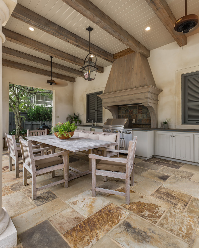 Exemple d'une très grande terrasse arrière chic avec une cuisine d'été, des pavés en pierre naturelle et une extension de toiture.