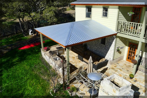 Cette photo montre une terrasse arrière chic de taille moyenne avec une cuisine d'été, des pavés en pierre naturelle et une extension de toiture.