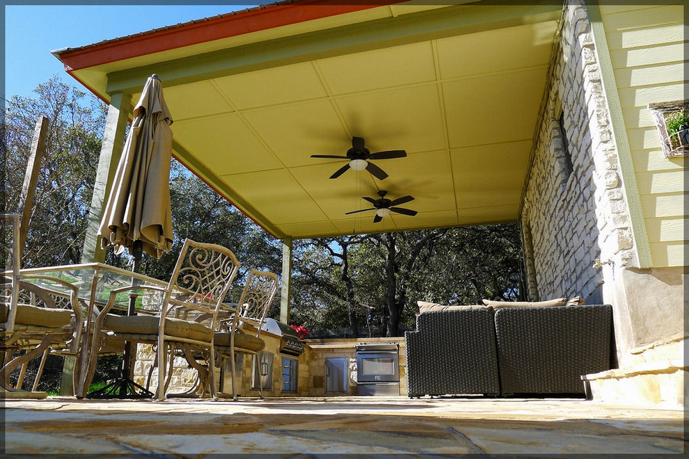 Immagine di un patio o portico chic di medie dimensioni e dietro casa con pavimentazioni in pietra naturale e un tetto a sbalzo
