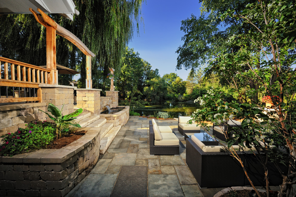 Idee per un ampio patio o portico design dietro casa con fontane e pavimentazioni in pietra naturale