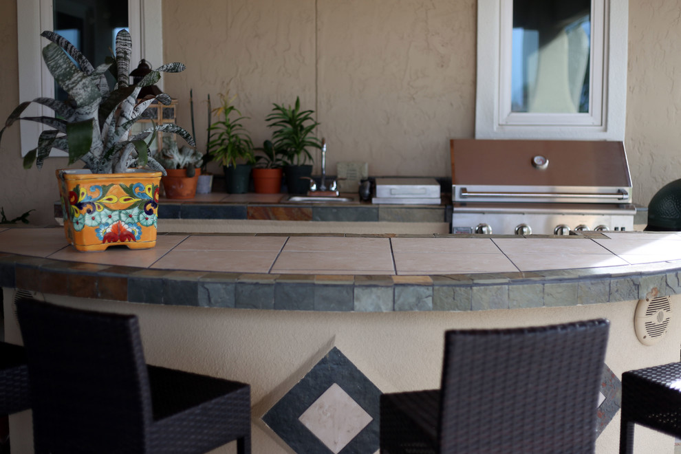 На фото: большой двор на заднем дворе в средиземноморском стиле с летней кухней, покрытием из каменной брусчатки и навесом