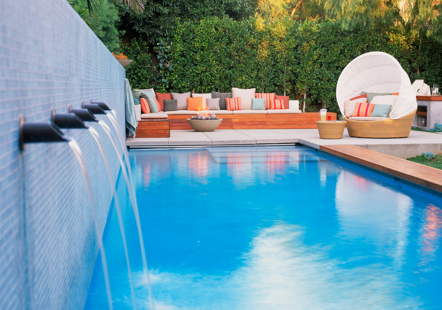 На фото: большой бассейн на заднем дворе в современном стиле с покрытием из бетонных плит с