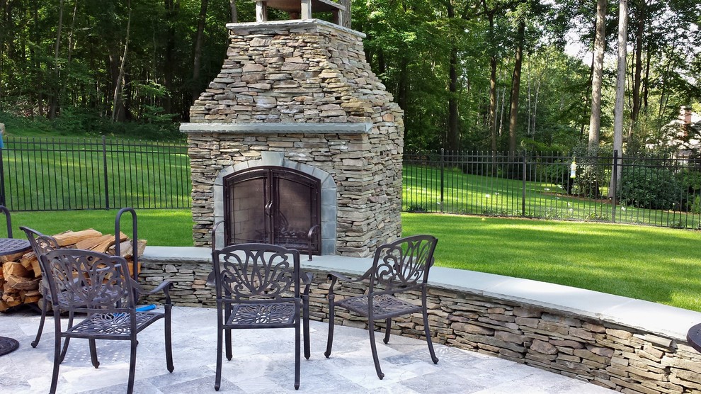 Example of a huge classic backyard stone patio design in New York with a fire pit