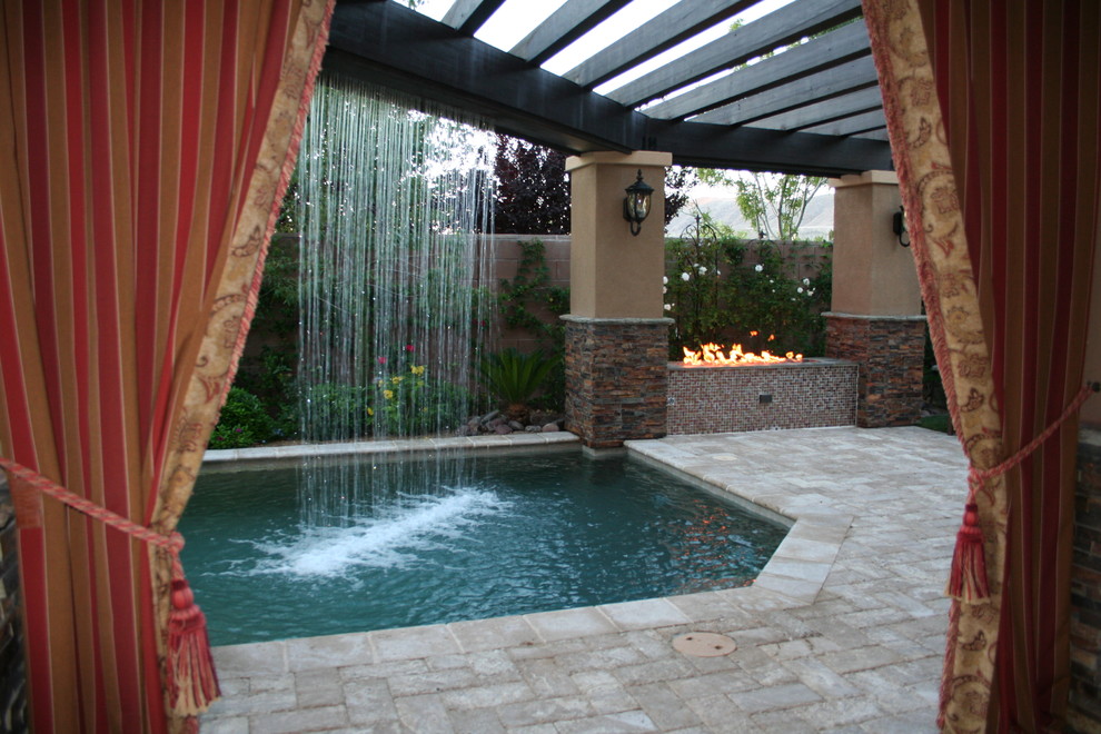 Example of a large tuscan backyard stone patio fountain design in Las Vegas with a pergola
